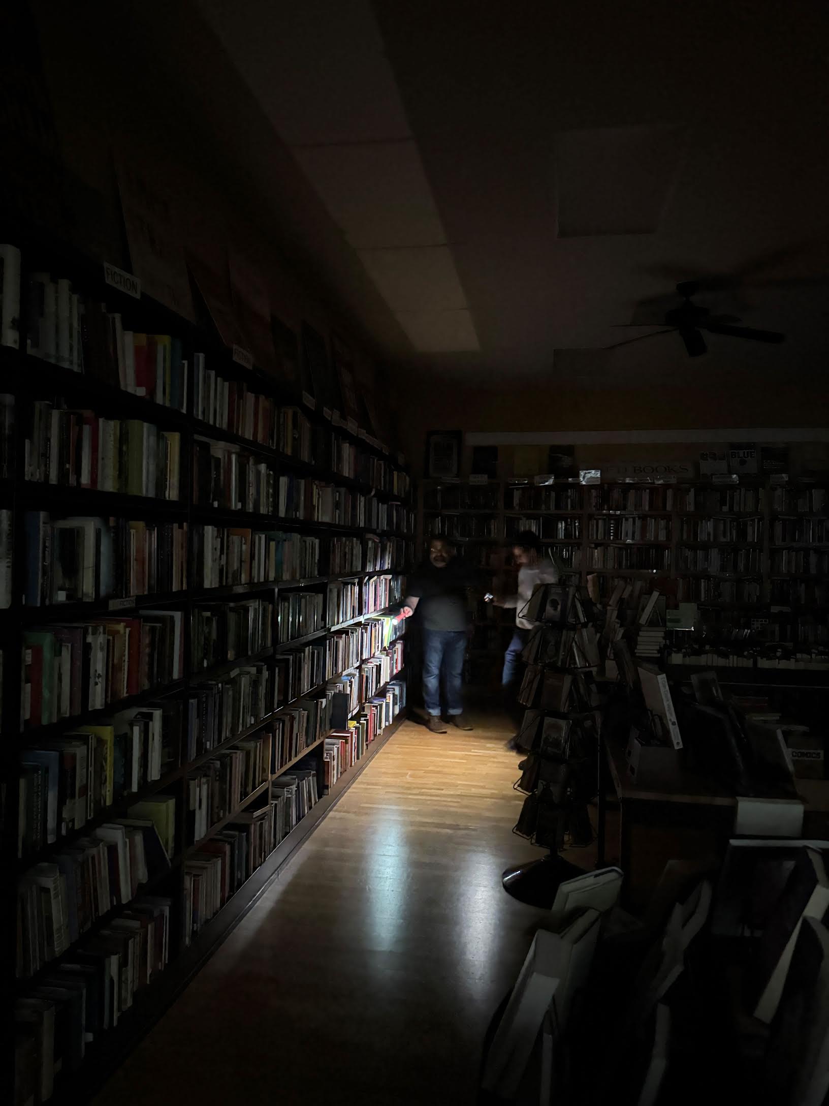 Flyleaf bookseller Dominic Louise helps a customer by flashlight. Photo credit: Credit Talia Smart, Floor Manager at Flyleaf